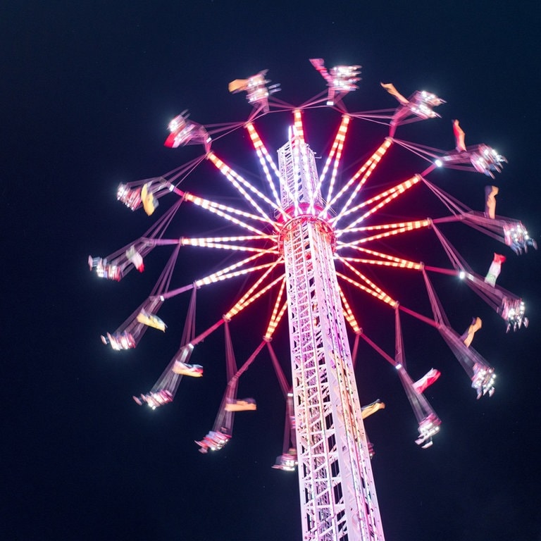 Ein Karussel auf einem Volksfest wie dem Wasen von unten fotografiert vor blauem Nachthimmel (Foto: Adobe Stock, Adobe Stock // Robert Kdot)