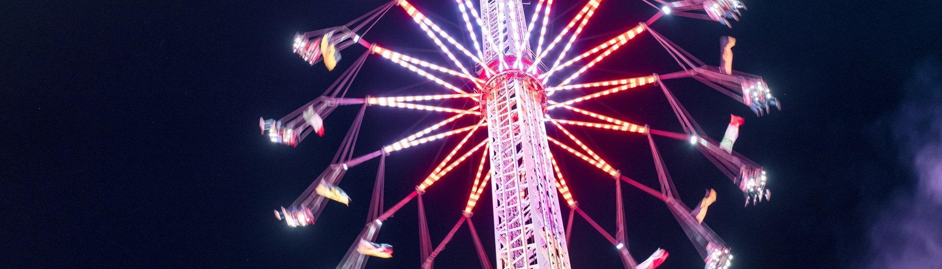 Ein Karussel auf einem Volksfest wie dem Wasen von unten fotografiert vor blauem Nachthimmel (Foto: Adobe Stock, Adobe Stock // Robert Kdot)
