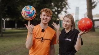 Fußball-Freestyler Jannik zeigt einen Fußballtrick, indem er den Ball auf seinem Zeigefinger balanciert. Daneben hält SWR3-Reporterin Corinne fragend die Hände nach oben. (Foto: SWR3, Ronny Zimmermann) Fußball-Freestyler Jannik zeigt einen Fußballtrick, indem er den Ball auf seinem Zeigefinger balanciert. Daneben hält SWR3-Reporterin Corinne fragend die Hände nach oben.