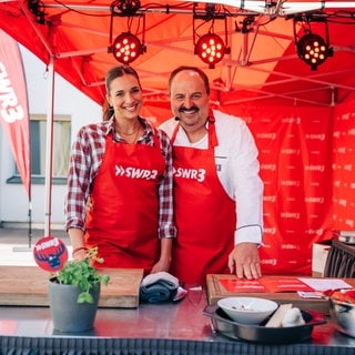 Johann Lafer und Sally stehen unter einem Pavillon beim großen SWR3 Grillen 2025.