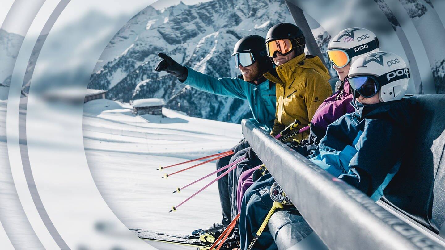 Skifahrende Familie in Winter-Ausrüstung in einer Gondel im Schnee vor Bergen. (Foto: Zillertaltourismus/Christoph Johann)