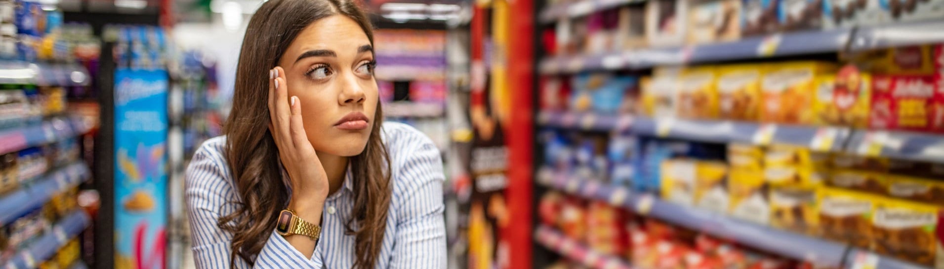Eine Frau steht mit ihrem Wagen im Supermarkt und schaut frustriert die Regale an (Foto: Adobe Stock Fotos/Dragana Gordic)