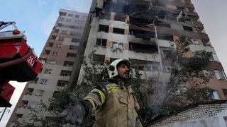 Ein Feuerwehrmann ist am Ort einer Explosion in einer Wohnanlage im Einsatz