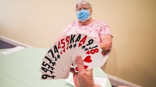 Damen spielen mit Maske Karten
