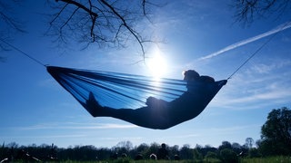 Mann liegt in Hängematte im Sonnenschein