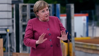 Angela Merkel breitet die Arme aus um zu beruhigen