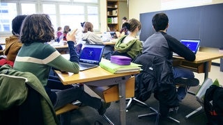 Schüler sitzen mit Laptop in der Schule