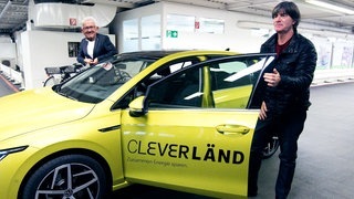 Kretschmann und Jogi Löw stehen vor Auto mit Cleverländ-Aufdruck