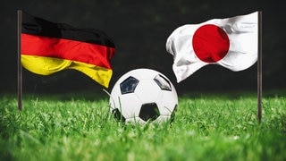 Die Flaggen von Deutschland und Japan hinter einem Fußball