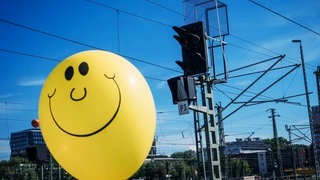 Luftballon mit Smiley auf Bahngleis