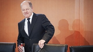 Olaf Scholz präsentiert lächelnd Schokolade