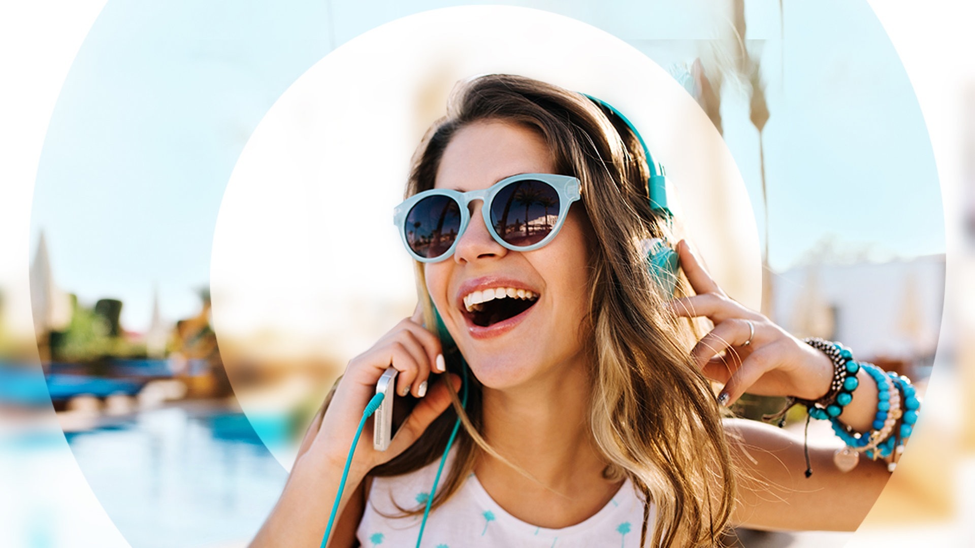 Junge Frau am Strand mit Sonnenbrille und Kopfhörern (Foto: Adobe Stock/Look!)