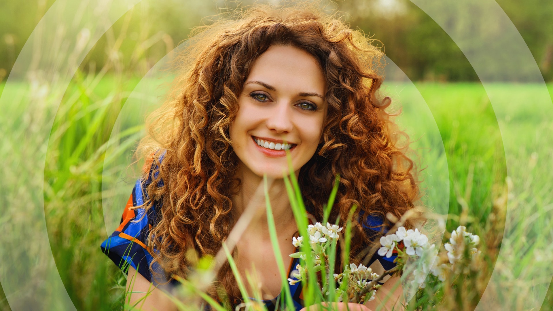 Junge Frau liegt im grünen Gras mit Blumen (Foto: Adobe Stock/Igor Link)