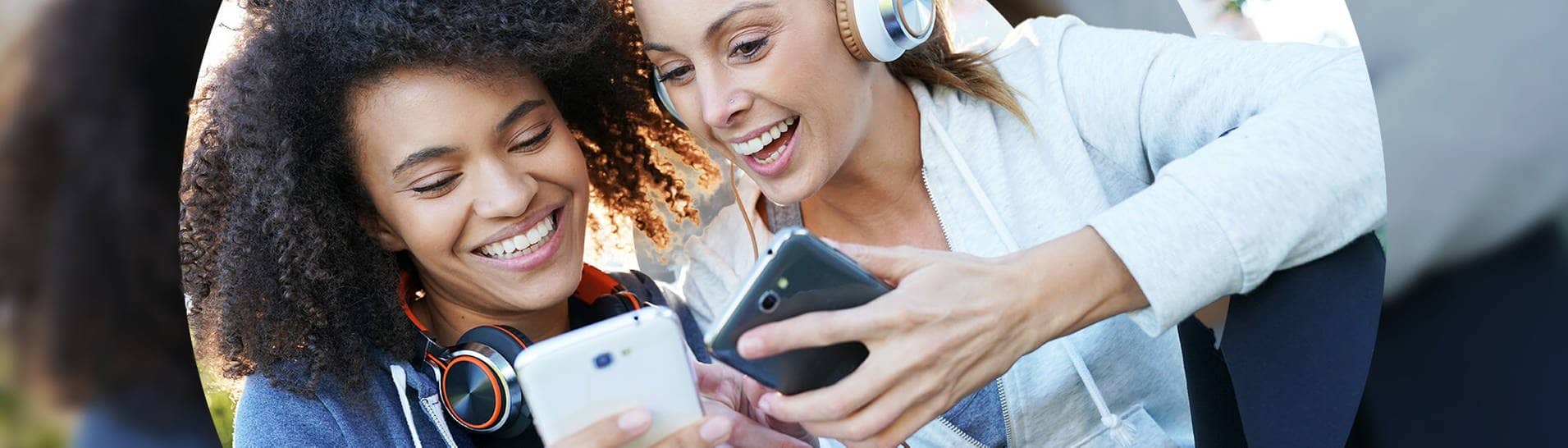 Zwei Frauen klicken auf Smartphones und hören dabei Musik. (Foto: Adobe Stock)