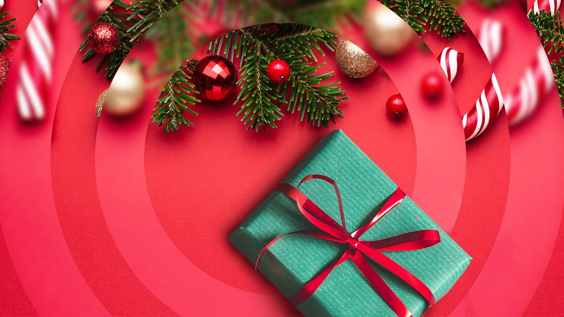 Tannenzweige, ein grün verpacktes Geschenk und rote Christbaumkugeln. (Foto: Adobe Stock Flaffy und Oleksandr Kotenko)