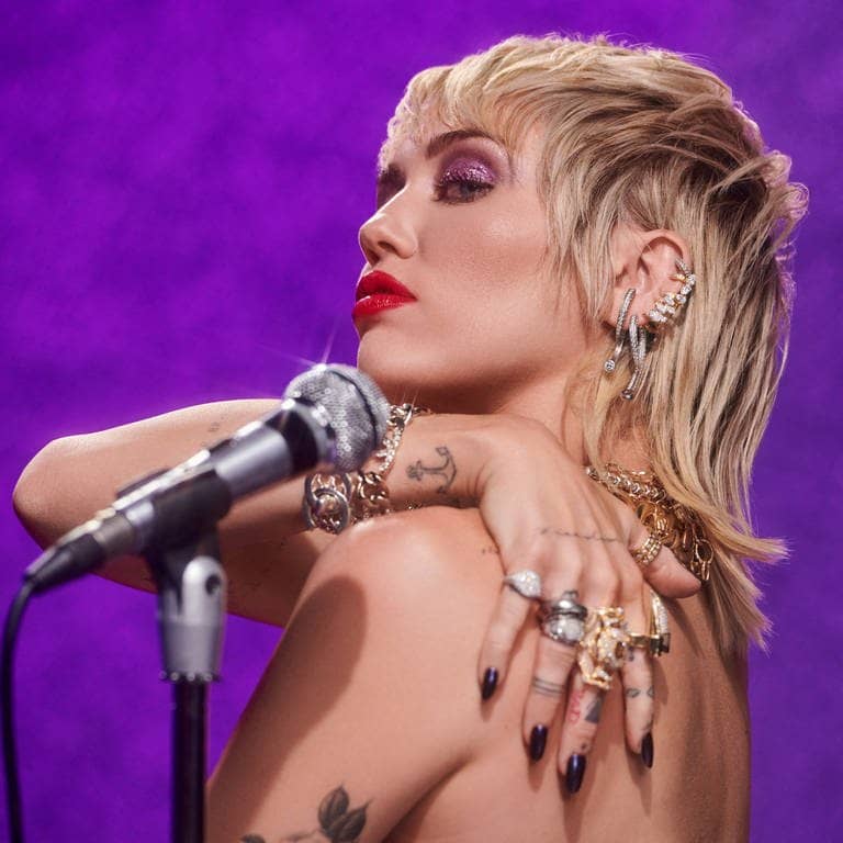 Die Sängerin Miley Cyrus vor einer lila Wand mit einem silbernen Mikrofon.  (Foto: Sony Music)