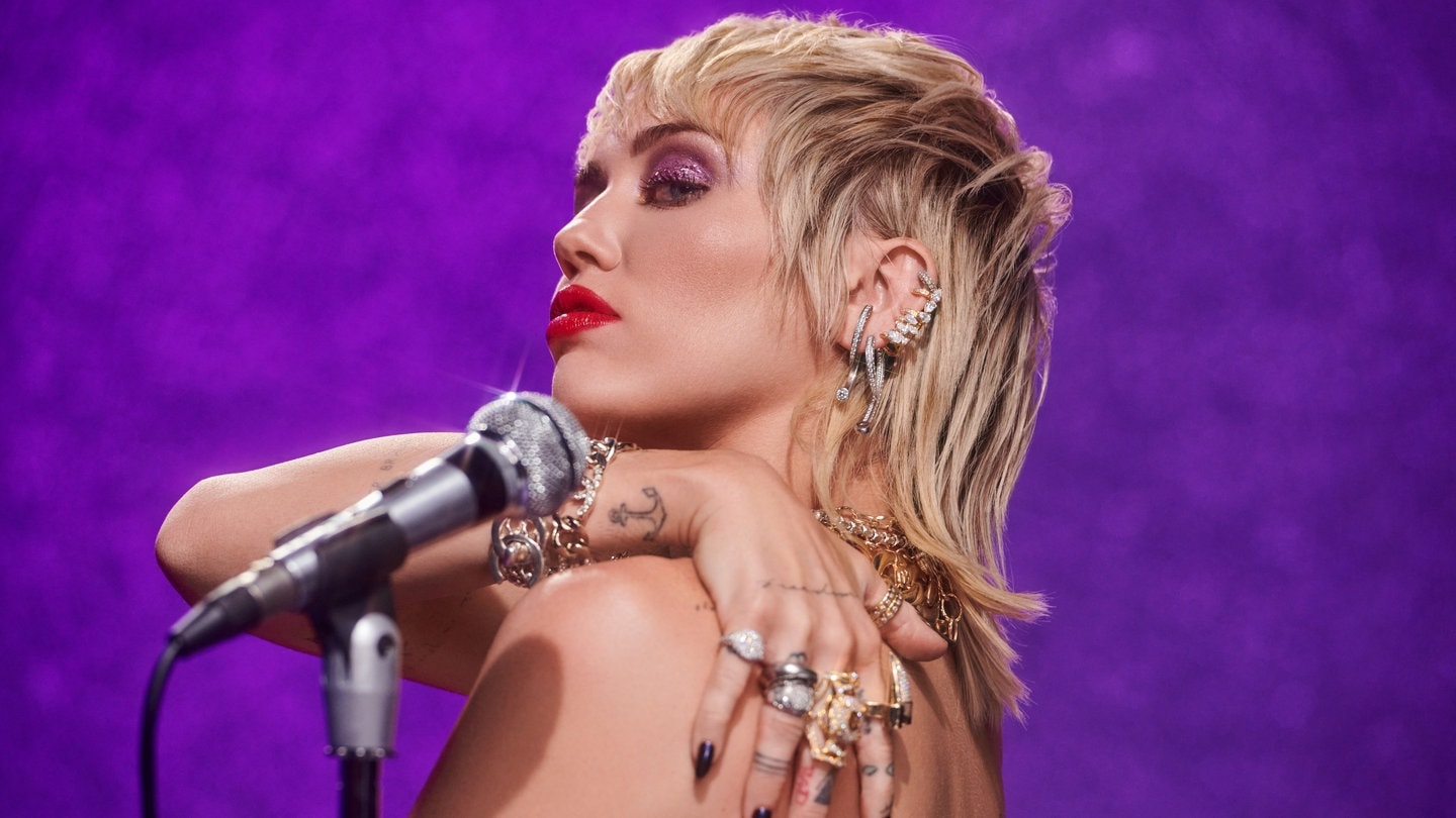 Foto: Sony Music Die Sängerin Miley Cyrus vor einer lila Wand mit einem silbernen Mikrofon. (Foto: Sony Music)