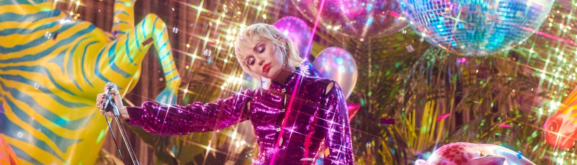 Die Sängerin Miley Cyrus vor einem bunten Hintergrund mit Discokugeln, Tierskulpturen und Luftballlons. (Foto: Sony Music)