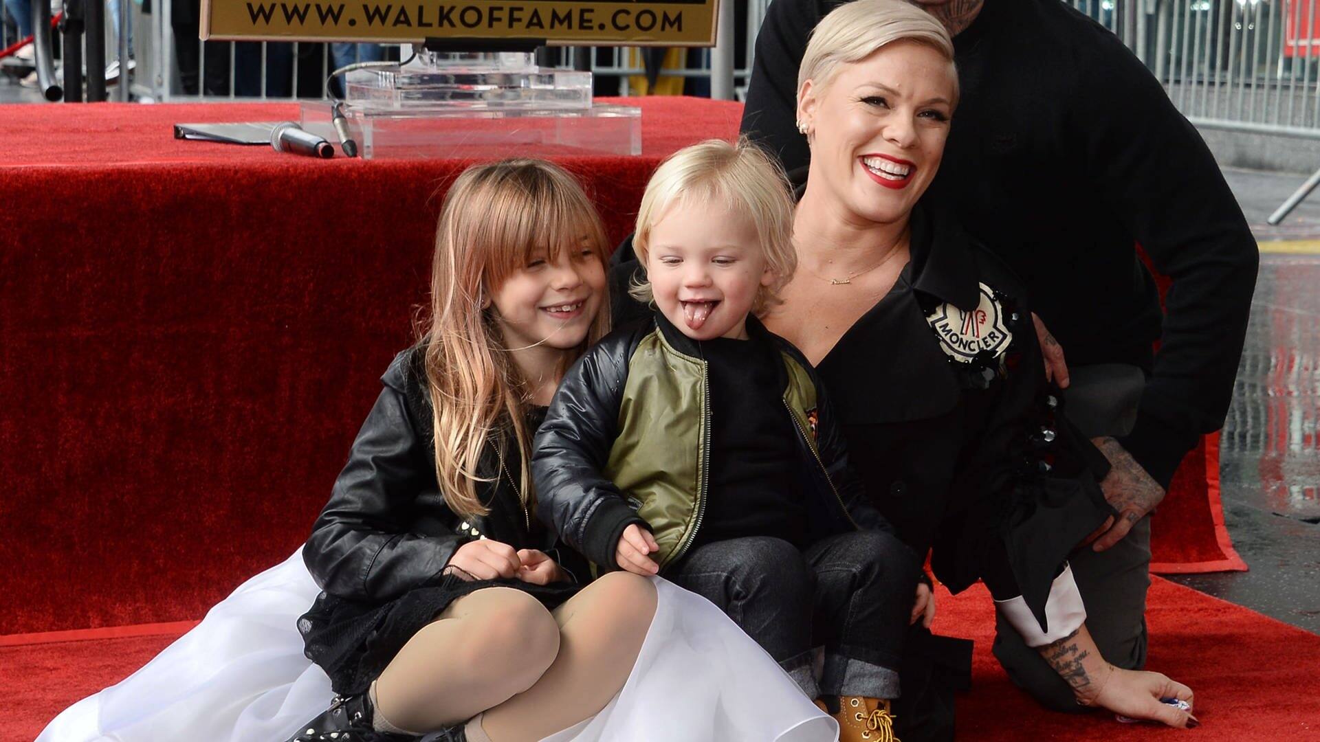 Sängerin Pink sitzt im weißen Kleid auf dem Walk of Fame bei ihrem Stern, gemeinsam mit ihren beiden Kindern und ihrem Mann (Foto: picture-alliance / Reportdienste, picture alliance / newscom | JIM RUYMEN)