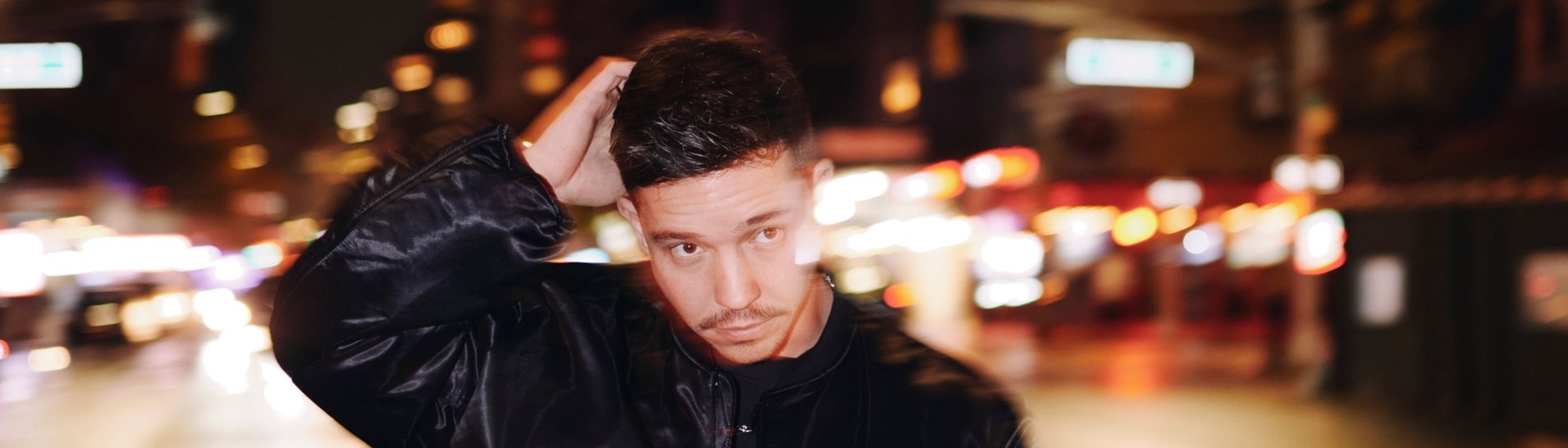 Der Sänger Nico Santos steht auf einer Straße, hinter ihm sind die Lichter einer Stadt zu sehen (Foto: Chrostoph Köstlin)