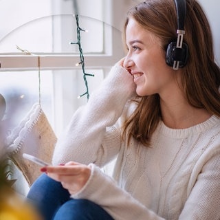 Frau hört Musik vor Christbaum