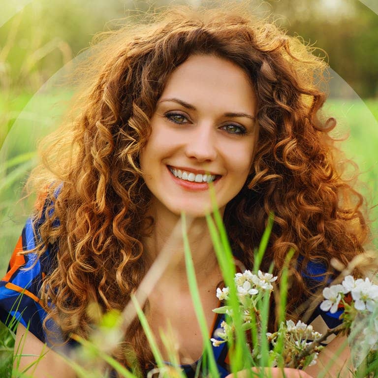 Junge Frau liegt im grünen Gras mit Blumen