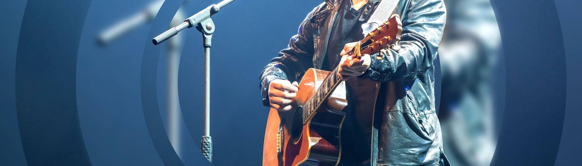Ein Musiker spielt bei einem Auftritt auf einer Akustik-Gitarre (Foto: Adobe Stock, v74)