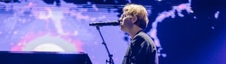 Der Sänger Tom Odell sitzt an einem schwarzen Flügel.