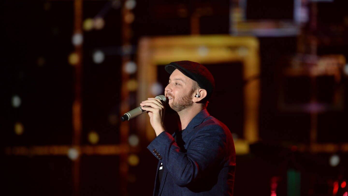Der Sänger Matt Simons hält ein Mikro in der Hand und trägt eine Mütze, er tritt beim Deutschen Radiopreis 2016 auf (Foto: picture-alliance / Reportdienste, dpa | Daniel Bockwoldt)