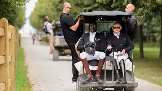 Snoop Dogg fährt eingekleidet im Reitoutfit in einem Golfcaddy zum Dressurreiten bei den Olympischen Spielen (Foto: picture-alliance / Reportdienste, picture alliance/dpa | Rolf Vennenbernd) Snoop Dogg fährt eingekleidet im Reitoutfit in einem Golfcaddy zum Dressurreiten bei den Olympischen Spielen