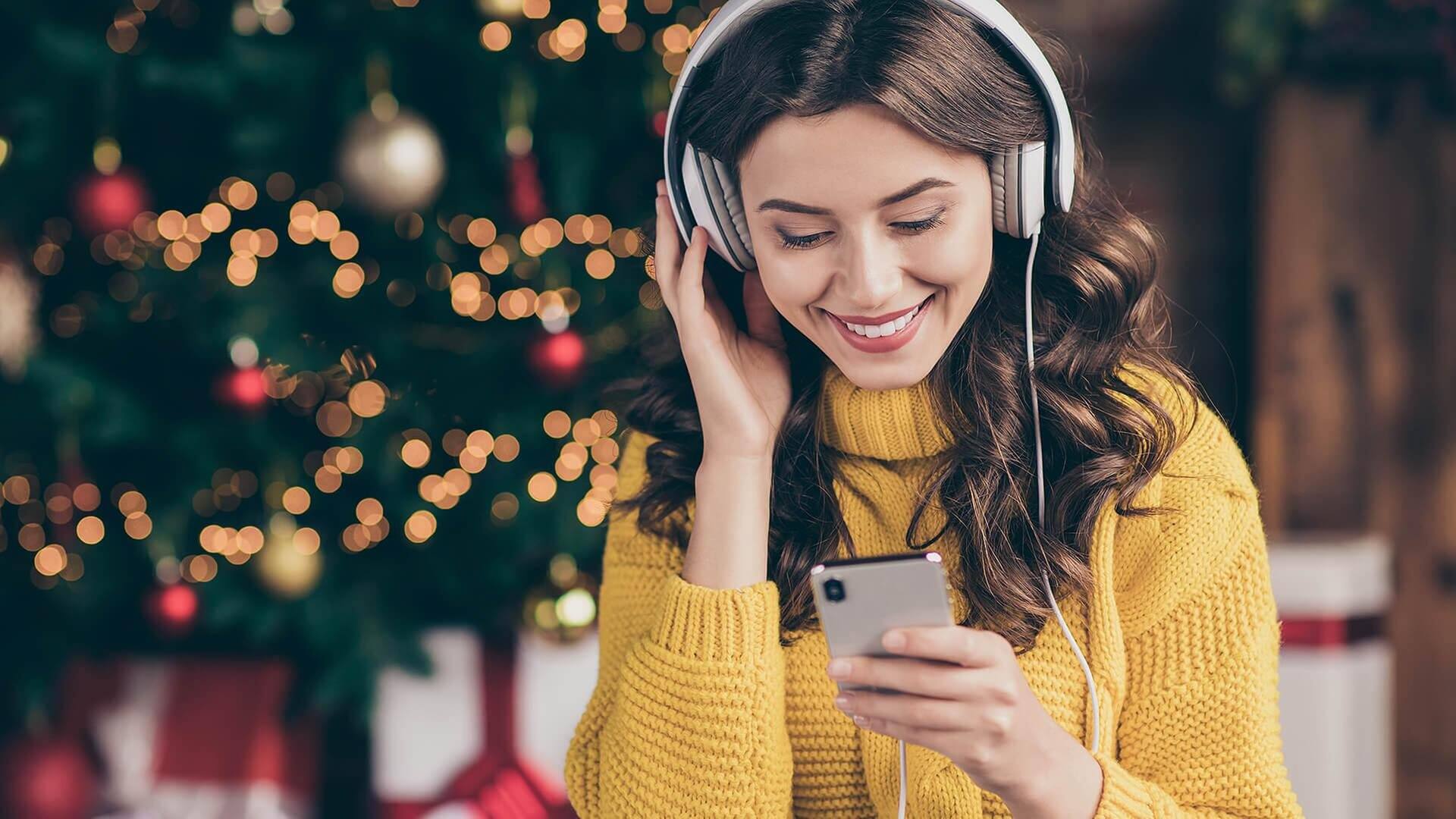 Frau hört Weihnachtssongs & Musik für Weihnachten (Foto: Adobe/deagreez)