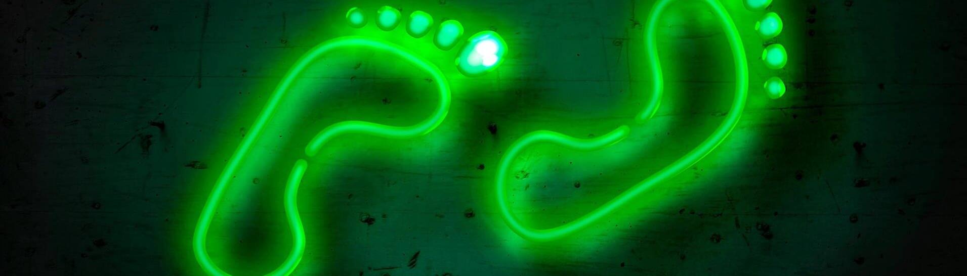 Grüne Neon-Fußabdrücke auf einer Wand – SWR3 New Pop goes green (Foto: Colourbox)