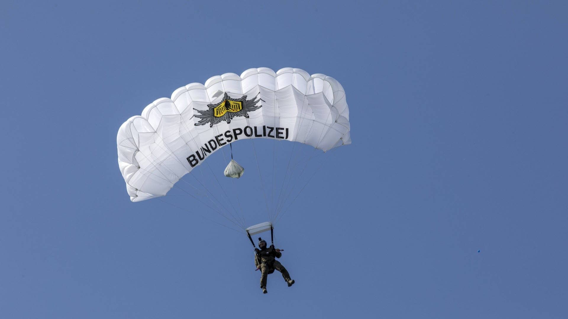Polizist der Spezialeinheit GSG9 mit weissem Fallschirm, auf dem Bundespolizei steht. (Foto: IMAGO, IMAGO / Jochen Tack)