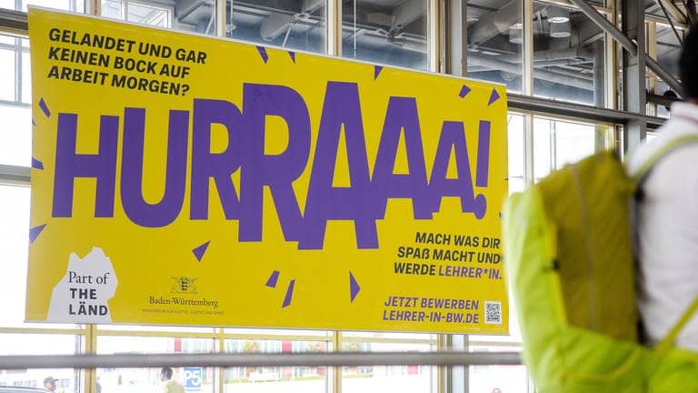 Ein Werbeplakat für den Beruf des Lehrers hängt am Flughafen in Stuttgart