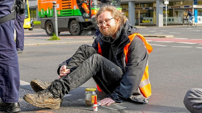 Ein Klimaaktivist hat sich auf die Straße geklebt