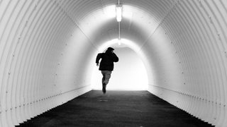 flüchtender junger Mann in einem Tunnel in schwarz-weiß gehalten