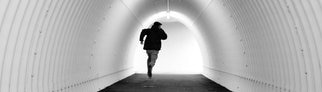 flüchtender junger Mann in einem Tunnel in schwarz-weiß gehalten