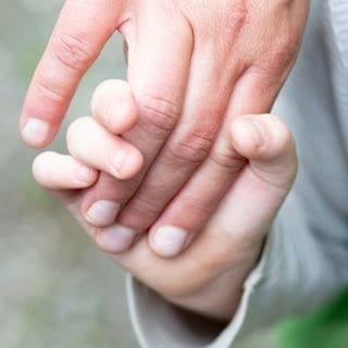 Ein Junge hält eine Frau an der Hand und steht für die positive Verbindung zwischen Simone und ihrem schwerstbehinderten Sohn Jonathan