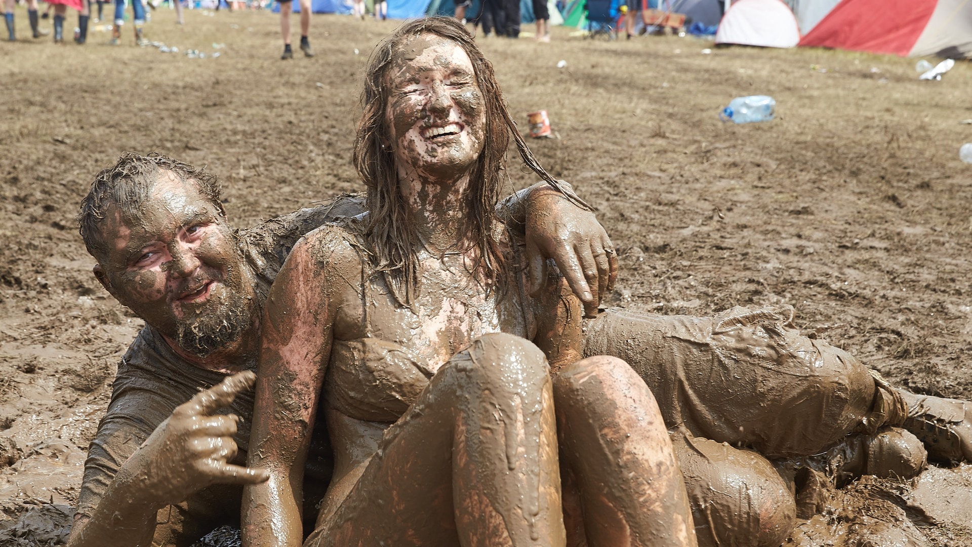 Foto: picture-alliance / Reportdienste, Thomas Frey Ein Mann und eine Frau wälzen sich beim Musikfestival Rock am Ring im Schlamm. (Foto: picture-alliance / Reportdienste, Thomas Frey)