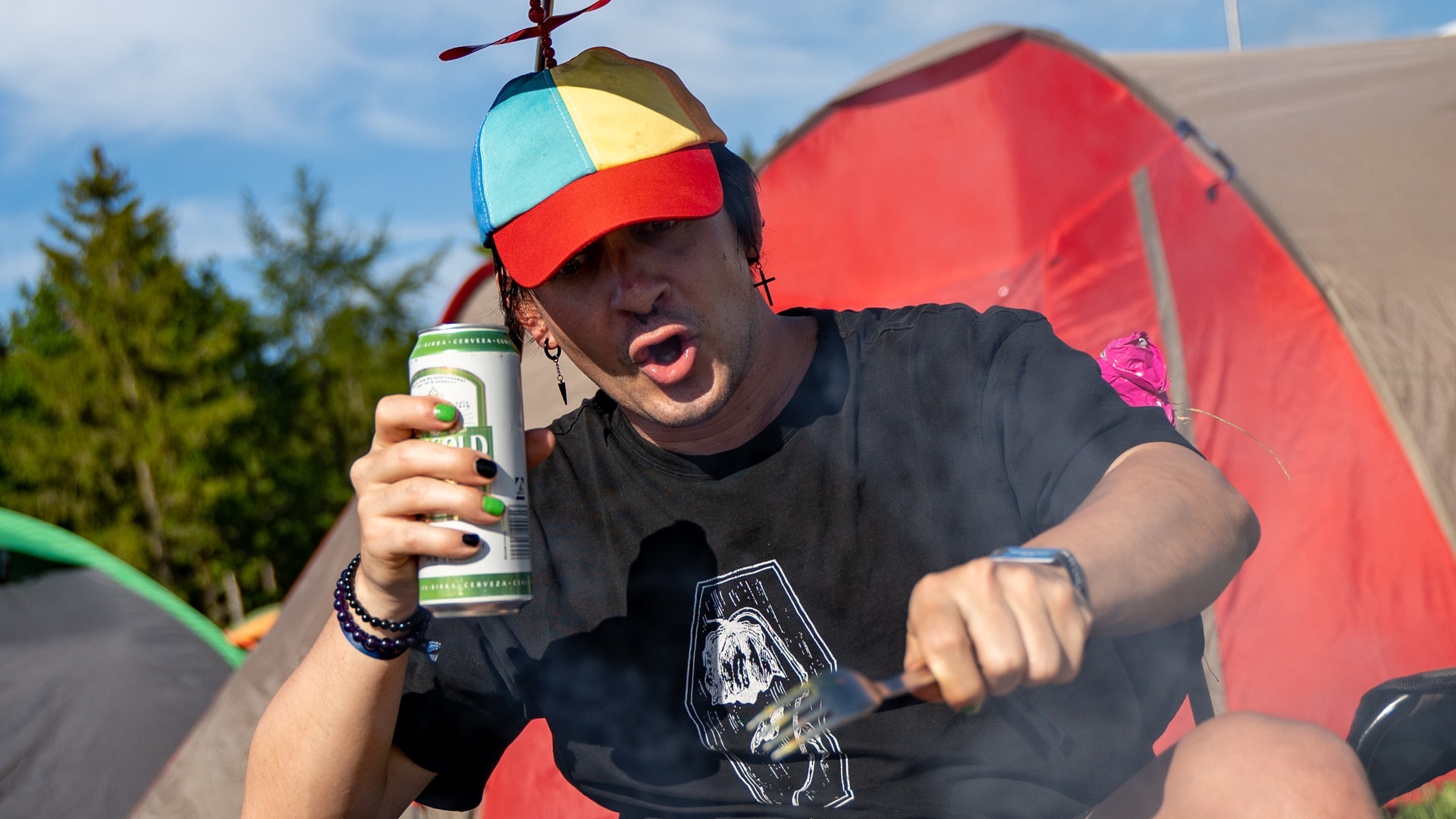 Foto: SWR3, SWR3 / Ronny Krautz Ein junger Mann sitzt auf einem Campingstuhl mit einem kleinen Sonnenschirm-Hut auf dem Kopf vor Zelten bei Rock am Ring (Foto: SWR3, SWR3 / Ronny Krautz)