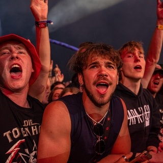 Junge Menschen stehen gemeinsam direkt vor der Bühne und feiern wie viele Fans bei Rock am Ring.