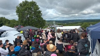 Menschen feiern bei der Biermesse auf dem Campingplatz bei Rock am Ring. Ein Mann hält ein Kreuz, das aus Bierdosen gebaut wurde, in der Hand. (Foto: SWR3) Menschen feiern bei der Biermesse auf dem Campingplatz bei Rock am Ring. Ein Mann hält ein Kreuz, das aus Bierdosen gebaut wurde, in der Hand.