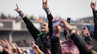 Eine junge Frau feiert bei Rock am Ring im Publikum und streckt beide Arme nach oben. (Foto: picture-alliance / Reportdienste, Picture Alliance) Eine junge Frau feiert bei Rock am Ring im Publikum und streckt beide Arme nach oben.