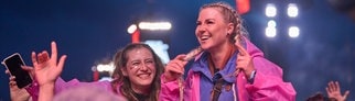 Rock am Ring 2025: Zwei junge Frauen tragen pinke Regenponchos bei Rock am Ring und feiern in der Menge.
