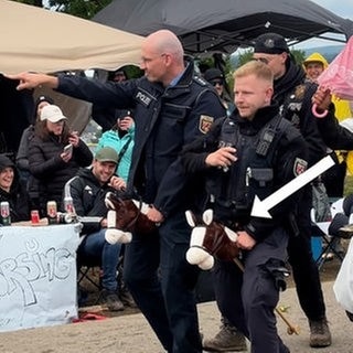 Auf dem Campingplatz bei Rock am Ring reiten zwei Polizisten in Uniform auf einem Steckenpferd.