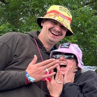 Ein Pärchen hält die Hände in die Kamera und zeigt aus Papier gebastelte Ringe auf dem Campingplatz bei Rock am Ring.