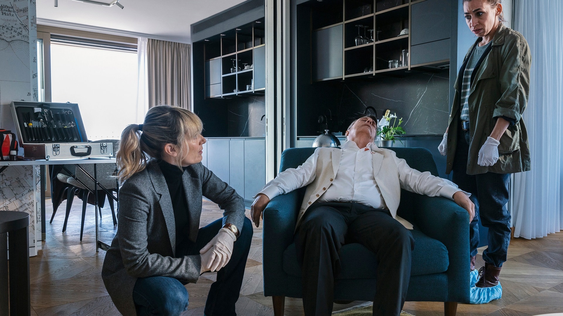 Foto: ard-foto s2-intern/extern, ARD Degeto / SRF / Sava Hlavacek Grandjean und Ott sind die Ermittlerinnen im Tatort aus der Schweiz und knien neben dem Opfer auf dem Sessel (Foto: ard-foto s2-intern/extern, ARD Degeto / SRF / Sava Hlavacek)