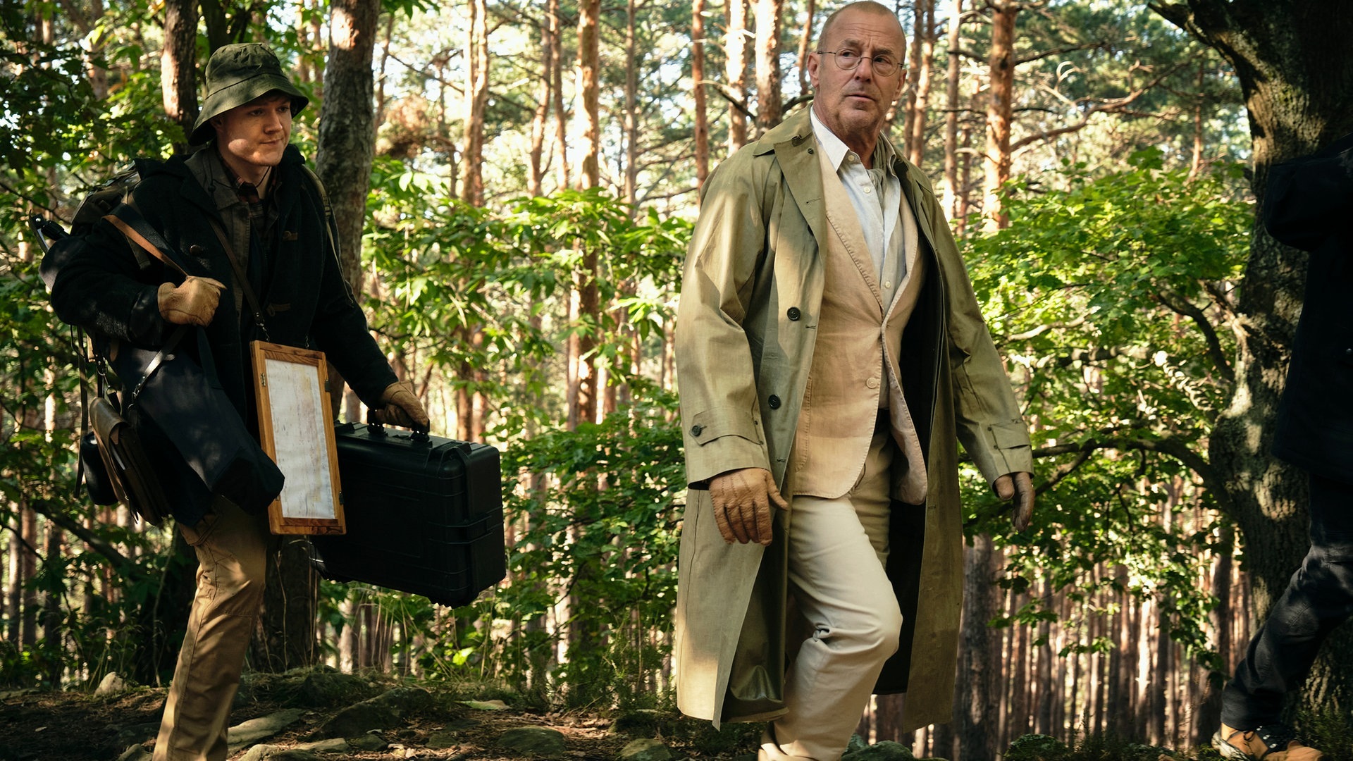 Foto: ard-foto s2-intern/extern, SWR / Benoît Linder Tatort-Kritik Ludwigshafen „Gold“: Der Forscher und sein Assistent stapfen durch einen Wald. Der Assistent trägt viel Gepäck mit sich. (Foto: ard-foto s2-intern/extern, SWR / Benoît Linder)