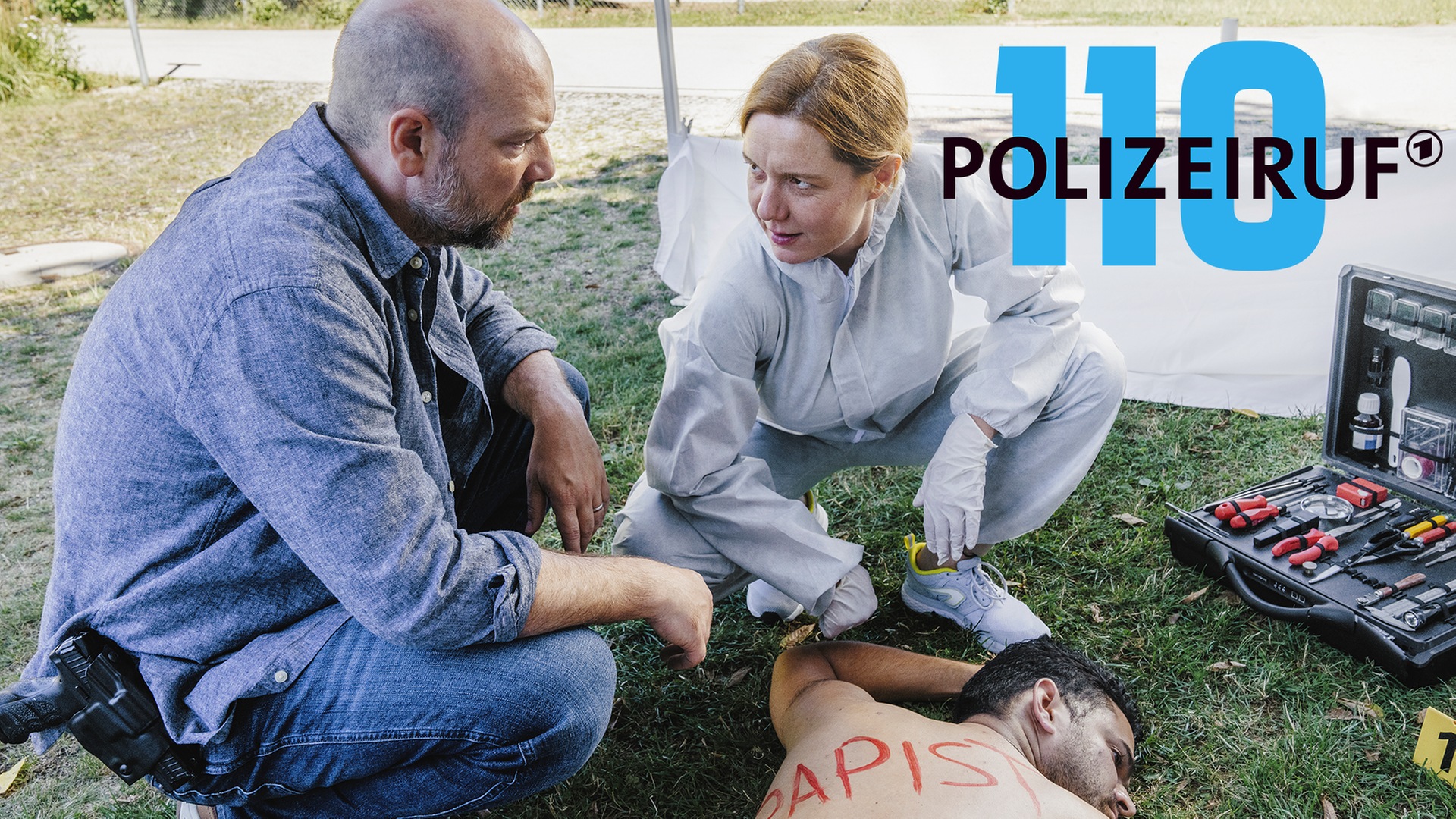 Polizeiruf-Kritik München: „Little Boxes“: Kriminalhauptkommissar Dennis Eden und Judith Flaman untersuchen den toten Dawoud Alrashid. (Foto: ard-foto s2-intern/extern, Ariane Krampe Filmproduktion/BR/Hendrik Heiden)