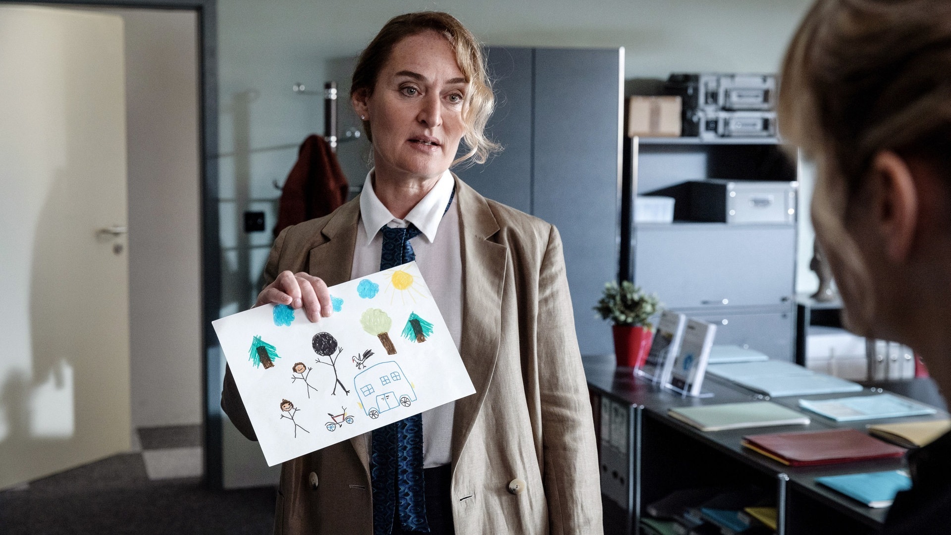 Foto: ard-foto s2-intern/extern, ARD Degeto / SRF / Sava Hlavacek Tatort-Kritik Zürich „Blinder Fleck“: Die Staatsanwältin zeigt eine Kinderzeichnung mit drei Personen in einem Wald. (Foto: ard-foto s2-intern/extern, ARD Degeto / SRF / Sava Hlavacek)
